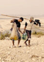 Nepali fishers walk up from a dried out lake with their catch from the day