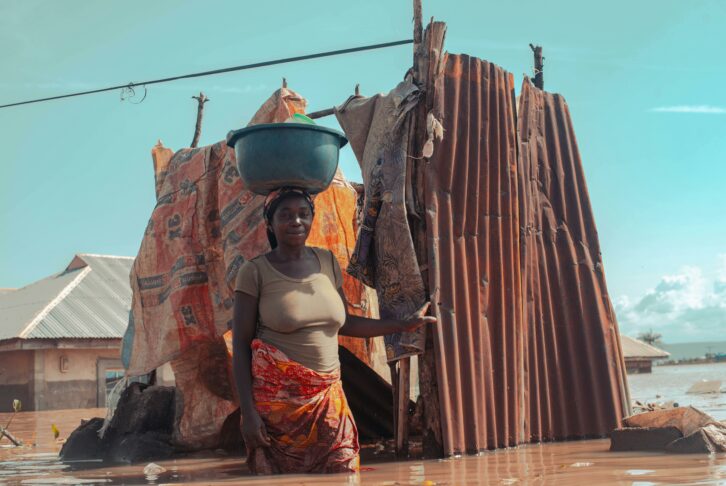 woman in a flooded area demonstrating the impact of climate change on vulnerable communities, a topic for COP29